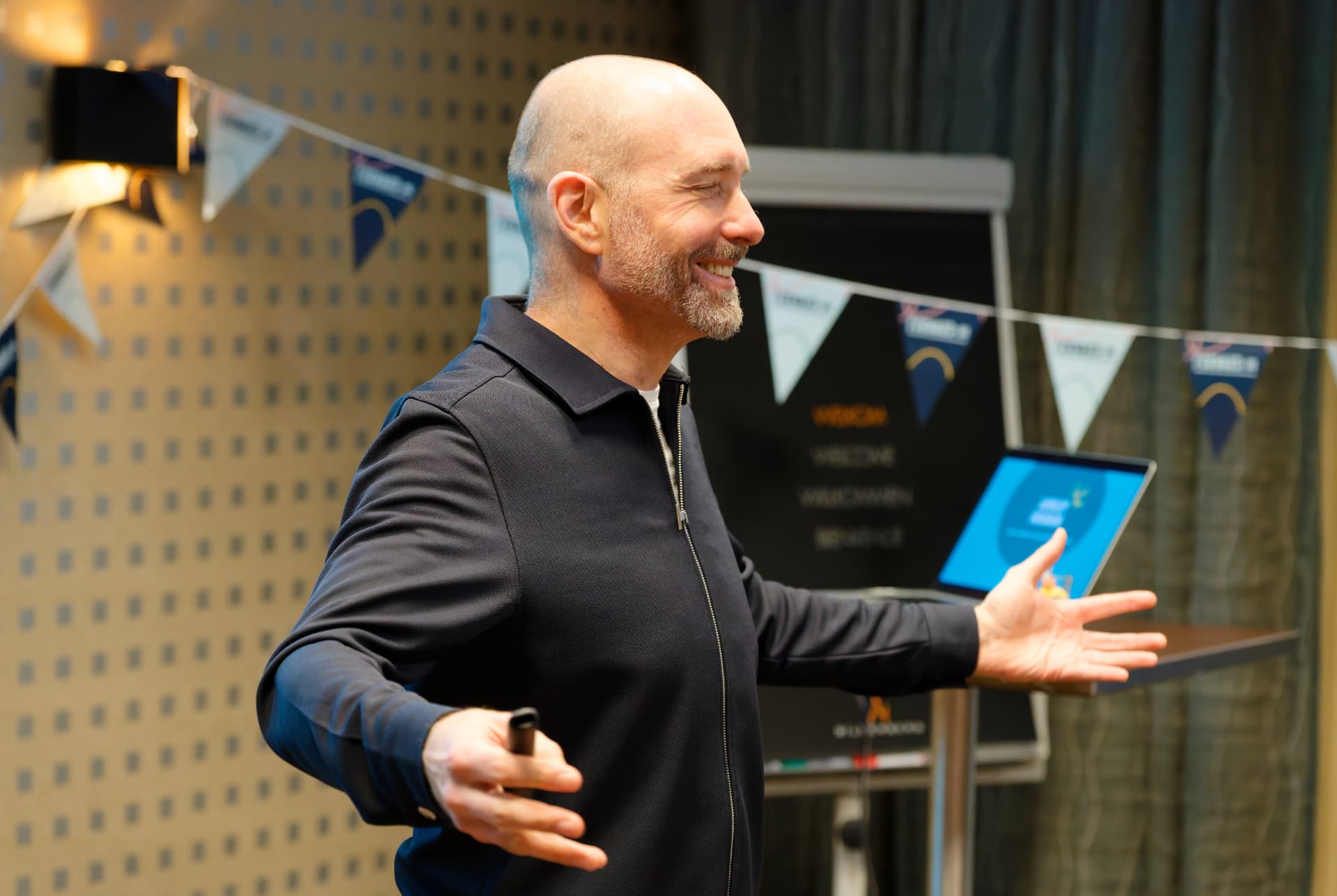 Ashley Usiskin smiling with arms open wide while speaking at an event