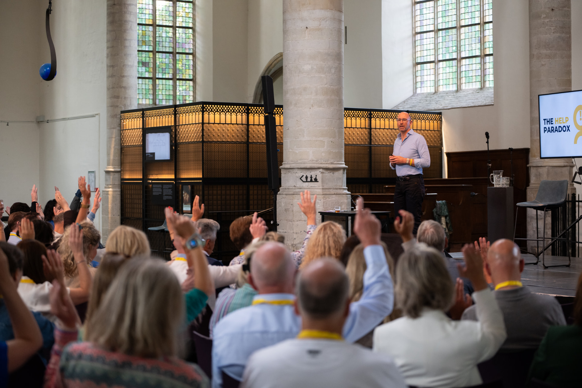 Ashley Usiskin speaking as audience members raise their hands in a church venue